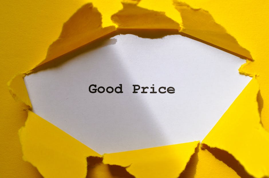 A close-up view of a white paper card embedded within torn yellow paper, revealing the message 'Good Price' printed in black text. The torn edges of the yellow paper create a rough, jagged border around the card, emphasizing the contrast between the vibrant yellow background and the plain white surface. The setting appears to be on a flat surface with the torn paper slightly raised, casting subtle shadows. This image, with its emphasis on the message, could relate to the concept of affordable or competitive pricing, pertinent in contexts such as waste management services or rubbish removal quotes, as provided by companies like Rubbish Collection Stockwell.